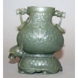 A CHINESE GREEN TURTLE-DRAGON JADE VASE, the mythical creature supporting on its back a vase