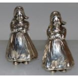 A PAIR OF EDWARD VII NOVELTY SILVER PEPPERETTES AS DUTCH WOMEN standing arms crossed 3.5ins high.