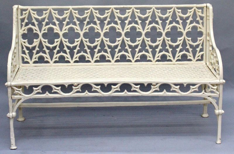 A GOOD GOTHIC DESIGN CAST IRON CREAM PAINTED GARDEN BENCH with Gothic design back, arms and seat.