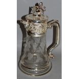 A GLASS AND SILVER PLATE CLARET JUG engraved with fruiting vines with lion finial.