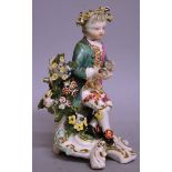 A LATE 18TH CENTURY DERBY FIGURE OF A BOY, seated with flowers in his hair.