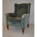 AN EDWARDIAN WING ARMCHAIR with tapering square legs and replacement castors.
