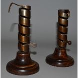 A PAIR OF EARLY BRASS CANDLESTICKS on circular wooden bases 6.5ins high.