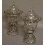 A SMALL PAIR OF CUT GLASS URN SHAPED VASES AND COVERS 12ins high.