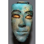 A SMALL PAINTED EGYPTIAN STONE MASK, 3.5ins long, mounted on a metal and wooden stand.