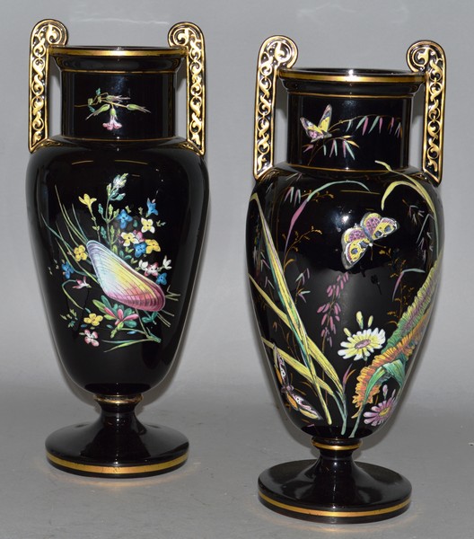 A GOOD PAIR OF VICTORIAN BLACK GLASS TWO HANDLED URNS painted with flowers and shells 12.5ins high.