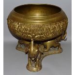 A LARGE INDIAN BRASS CIRCULAR BOWL on a stand supported by three elephants. 14ins diameter.