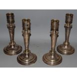 A SET OF FOUR CIRCULAR CANDLESTICKS on loaded bases 12ins high.