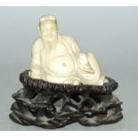 AN EARLY 20TH CENTURY CHINESE CARVED IVORY FIGURE OF A RECLINING SAGE, together with a carved and