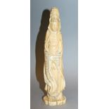 A JAPANESE CARVED IVORY FIGURE OF KWANNON, circa 1900, the Goddess standing on a shaped base in