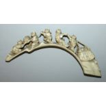 AN EARLY 20TH CENTURY SIGNED JAPANESE IVORY CARVING, of men hauling fruit over a rocky bridge, an