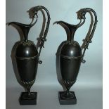 A PAIR OF REGENCY SLENDER BRONZE EWERS on square bases. 13ins high.