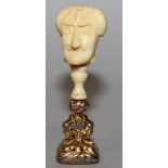 AN AMUSING GILT METAL AND CARVED IVORY SEAL, the rounded rectangular armorial incised intaglio