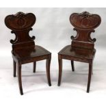 A GOOD PAIR OF REGENCY MAHOGANY HALL CHAIRS, with carved shaped backs, solid seats, reeded front