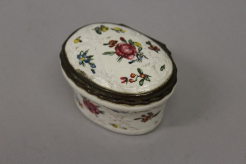 A BILSTON ENAMEL OVAL SNUFF BOX AND COVER painted with roses 2.5ins wide.