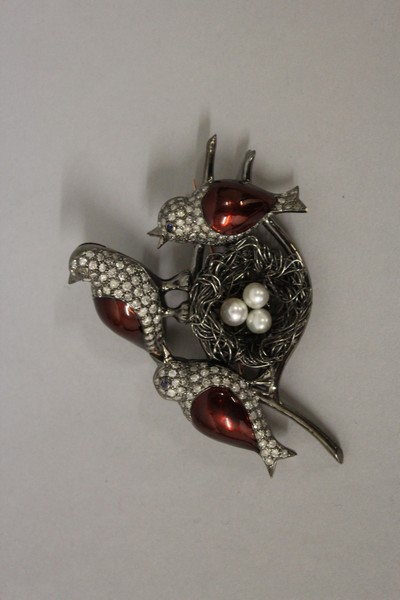 A DIAMOND SET BROOCH, THREE ENAMEL BIRDS with nest with three pearl eggs.