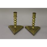 A PAIR OF EARLY BRASS CANDLESTICKS on triangular bases 6ins high.