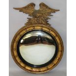 A GEORGE IV GILTWOOD CIRCULAR CONVEX MIRROR with eagle surmount. 18ins diameter, 2ft 10ins high.