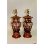 A PAIR OF BOHEMIAN CRANBERRY LAMPS with clear cut decoration of fruiting vines, supported on