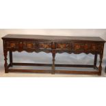 AN 18TH CENTURY STYLE OAK DRESSER BASE, the twin planked top over three geometrically moulded