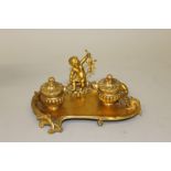 A GOOD SMALL 19TH CENTURY FRENCH ORMOLU INKSTAND with cupid and two ink pots 8ins wide.