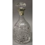 A SILVER TOP CUT GLASS DECANTER AND STOPPER.