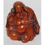 AN UNUSUAL SIGNED JAPANESE AMBER-LIKE NETSUKE OF HOTEI, seated with his head resting on one hand,