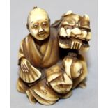 A 19TH/20TH CENTURY CARVED & STAINED IVORY NETSUKE OF A MAN & BOY, in the company of a buddhistic