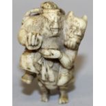 A 19TH CENTURY JAPANESE BONE IVORY NETSUKE OF SHOKI GRAPPLING WITH AN ONI, 1.8in high.