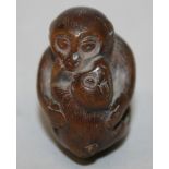 A 19TH CENTURY JAPANESE CARVED WOOD NETSUKE OF A MONKEY EMBRACING ITS YOUNG, 1.75in long & also 1.
