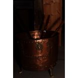 A copper log bin on three brass paw feet and three copper warming pans with wooden handles