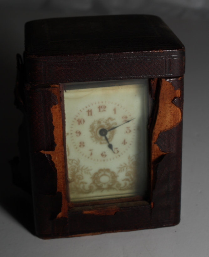 A brass framed carriage clock with gilt decorated cream dial and travelling case