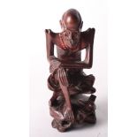 An oriental carved hardwood figure of a seated laughing Lohan, 8" high