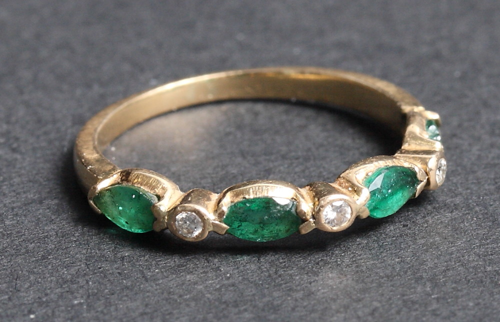 A yellow gold dress ring set emeralds and diamonds