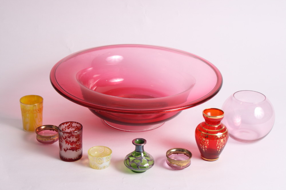 A ruby glass bowl with folded rim and other items of coloured glass
