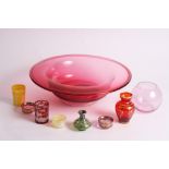 A ruby glass bowl with folded rim and other items of coloured glass