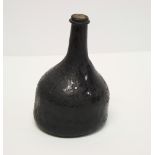 An 18th Century blown glass wine bottle of squat bulbous form, 7" high