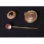 An engine turned circular gold locket, a hardstone mounted stick pin and a yellow metal brooch