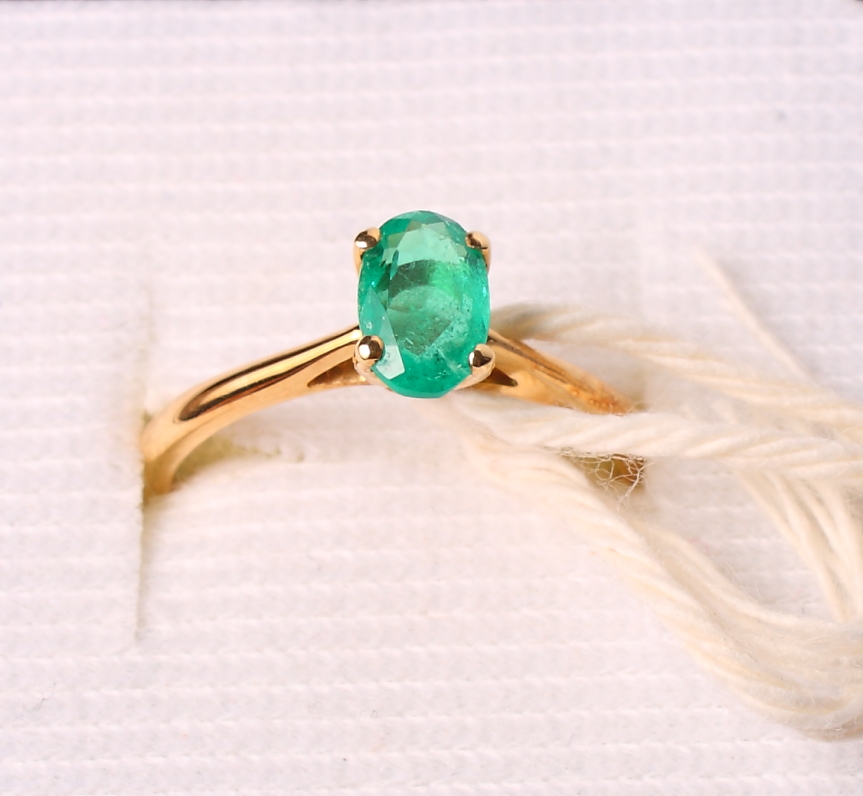 A single stone emerald ring on 18ct gold shank