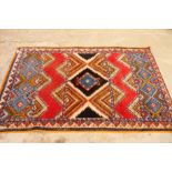 A Caucasian design rug decorated multi-coloured lozenge on a red ground, 80" x 44" approx