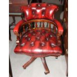 A mahogany desk elbow chair, button upholstered in a red leather, on castored supports