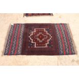 An Afghan Belouch rug decorated central medallion on a dark blue ground, 56" x 33" approx