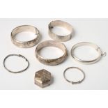 Six silver bangles and a silver pill box containing three silver coins