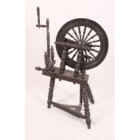 A dark stained wooden treadle spinning wheel
