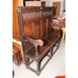 A 17th Century design oak settle with panelled back, on turned supports, 58" wide