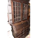 An early 20th Century dark stained Jacobean design oak bureau bookcase, the upper section enclosed