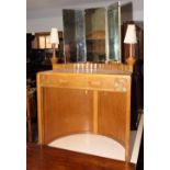 A child's Art Deco concave dressing table with triple plate mirror flanked lamps over single