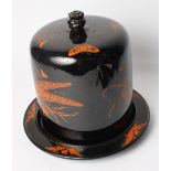 A Victorian black glazed Stilton cheese dish and cover decorated ferns and butterflies in red