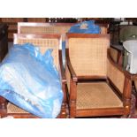 A stained as mahogany three-seat settee with double caned back and sides and two matching armchairs,