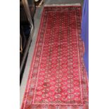 A Bokhara runner decorated three rows of guls on a red ground, 82" x 27" approx